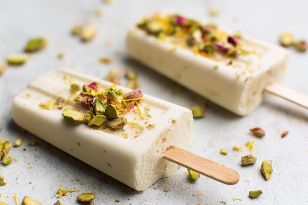 Mango kulfi mixture being stirred in a pan with milk and mango pulp.