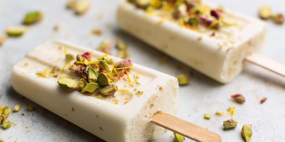 Mango kulfi mixture being stirred in a pan with milk and mango pulp.