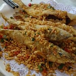 Crispy golden-brown spicy fried fish served hot with lemon wedges and chutney