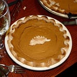 Fresh pumpkin pieces, spices, and baking ingredients prepared on a kitchen counter for a pumpkin recipe.