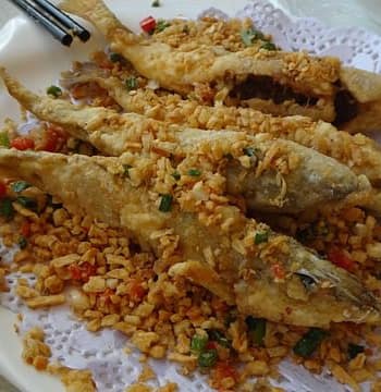 Crispy golden-brown spicy fried fish served hot with lemon wedges and chutney
