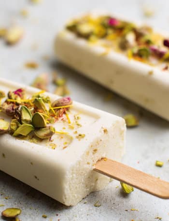Mango kulfi mixture being stirred in a pan with milk and mango pulp.