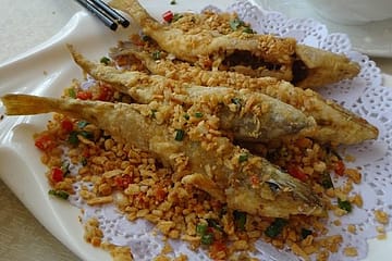 Crispy golden-brown spicy fried fish served hot with lemon wedges and chutney