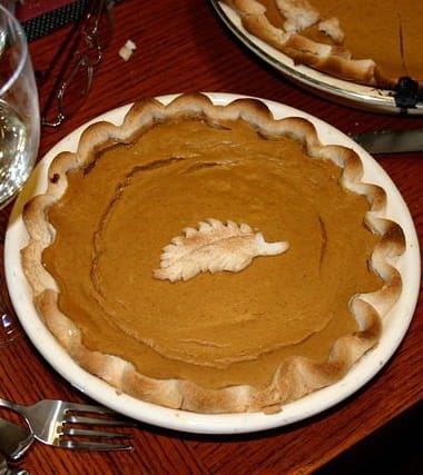 Fresh pumpkin pieces, spices, and baking ingredients prepared on a kitchen counter for a pumpkin recipe.