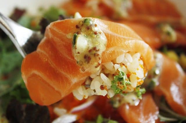 Step-by-step cooking process for Salmon Rice Bowl — searing salmon fillets, preparing rice, and mixing colorful vegetables and sauces.