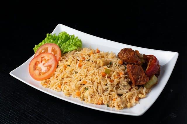 Stir-frying rice and vegetables in a wok for Fried Rice Recipe