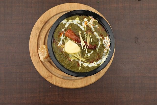 Close-up of creamy Palak Paneer showing spinach gravy and paneer cubes garnished with cream