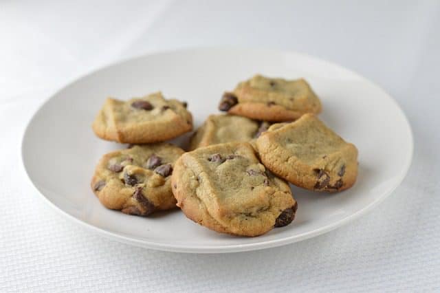 Chocolate chip cookies baking on a tray in the oven, turning golden brown.